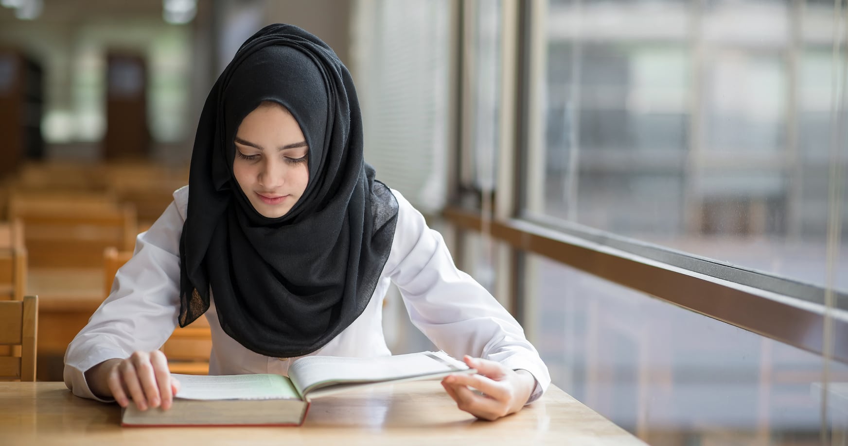 Muslim girl studying at the library.
