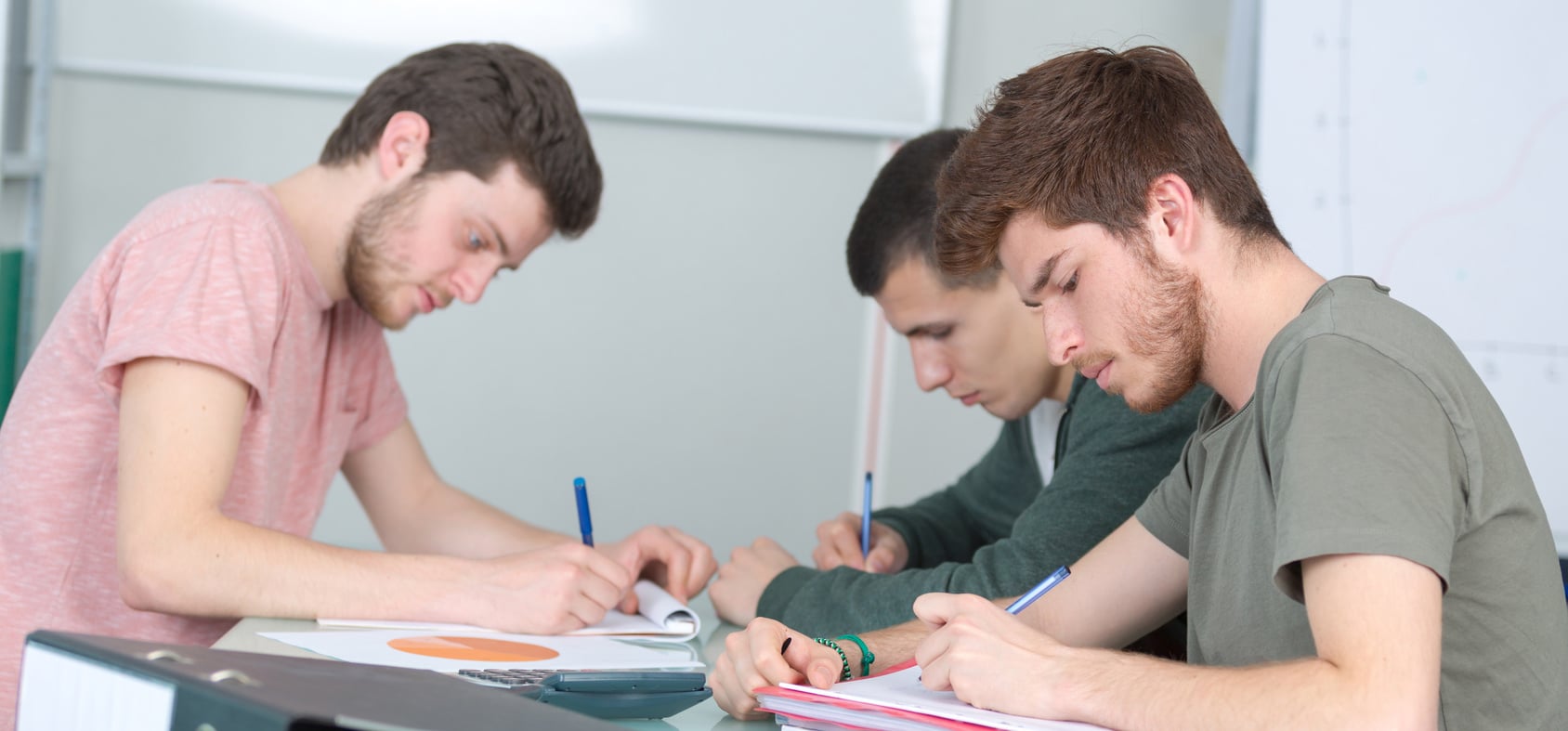 Young men sat at desk writing