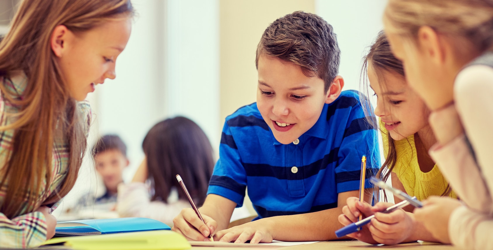 education, elementary school, learning and people concept - group of school kids with pens and papers writing in classroom